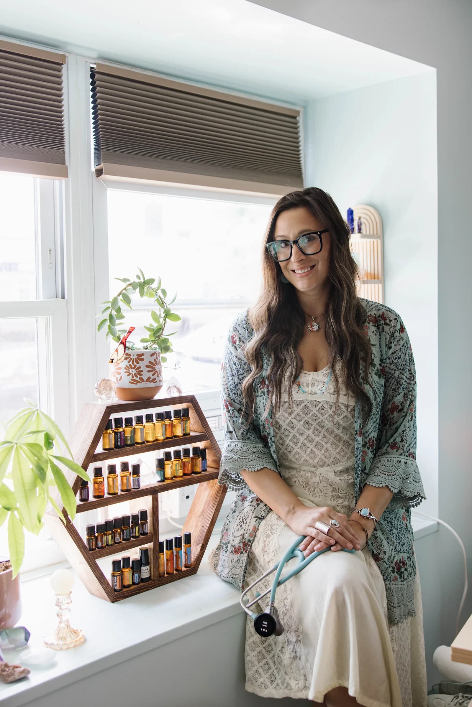 Alley Tuttle seated by a window with plants and crystals