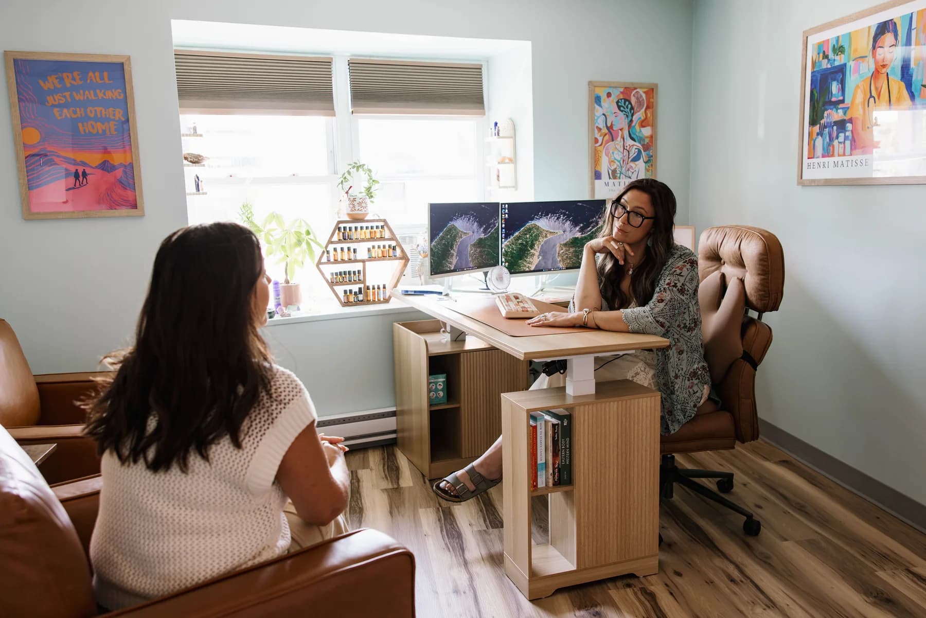 Alley Tuttle listens to a colleague across her desk at Apotheosis Health